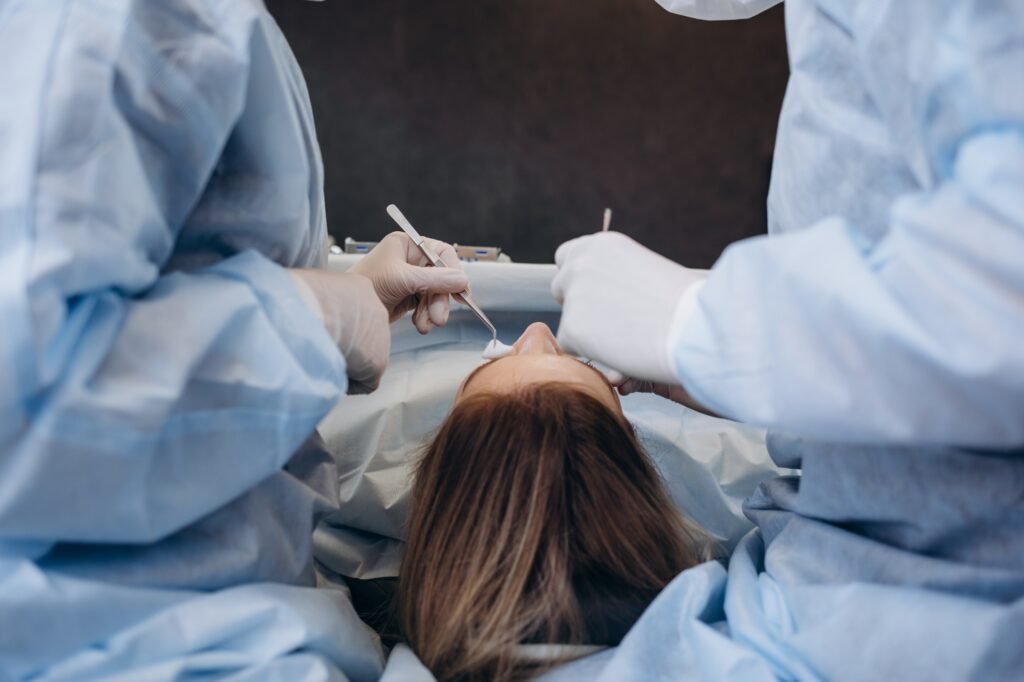 Surgeon and his assistant performing cosmetic surgery on nose in hospital operating room.